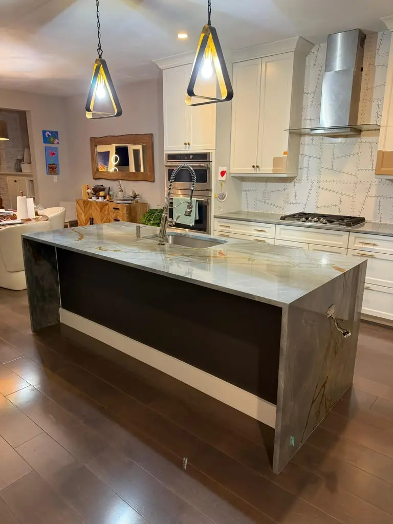 Large stone kitchen island with waterfall edges and integrated sink